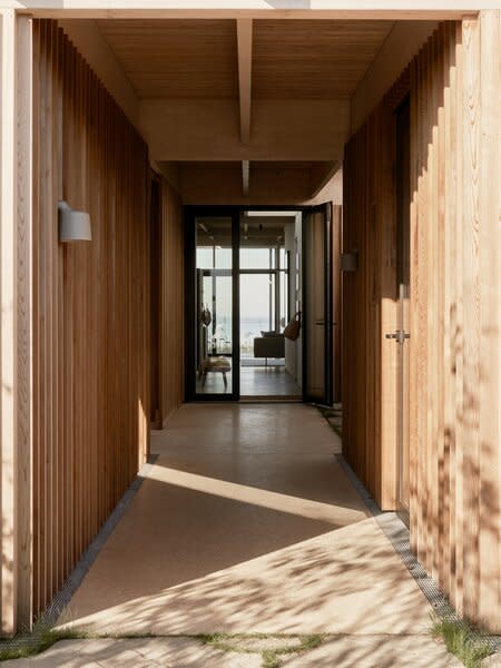 The entrance to the home is through a timber-clad passageway that leads to a guest annexe, a utility shed, and the main house. Whilst traditional Danish summer houses are often clad in dark timber, this contemporary interpretation of the typology inverts expectation by using a light Canadian cedar cladding—most expressively in this walkway.