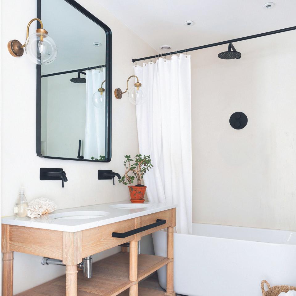 Double hand basin in a wooden vanity unit with a bath and white shower curtain