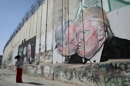 A woman looks at a mural depicting U.S. President Donald Trump and Israeli Prime Minister Benjamin Netanyahu on the controversial Israeli barrier in the West Bank city of Bethlehem October 29, 2017. REUTERS/Ammar Awad