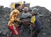 In this Oct. 23, 2019, photo, laborers lift a large basket filled with coal before loading it into a truck for transportation in the village of Godhar in Jharia, a remote corner of eastern Jharkhand state, India. The fires started in coal pits in eastern India in 1916. More than a century later, they are still spewing flames and clouds of poisonous fumes into the air, forcing residents to brave sizzling temperatures, deadly sinkholes and toxic gases. (AP Photo/Aijaz Rahi)