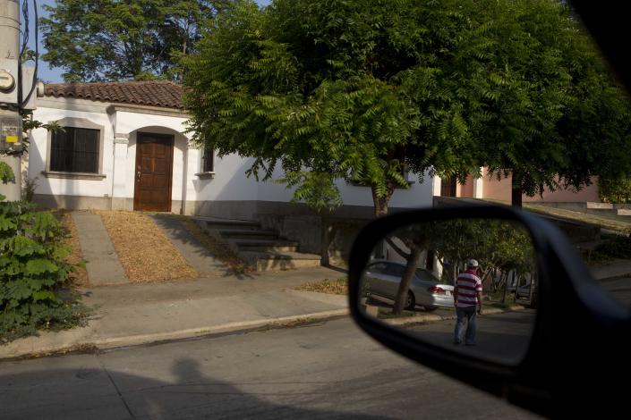 In this Wednesday, May 7, 2014 photo, a security guard is reflected in a car mirror in front of the house where U.S. citizen William James Vahey lived, near the American Nicaraguan School in Managua, Nicaragua where he worked as teacher from 2013-2014. Vahey, 64, killed himself on March 21, 2014 - two days after agents in Houston filed for a warrant to search a computer thumb drive that belonged to him. The storage device contained pornographic images of at least 90 boys, ages 12 to 14, who appeared to be drugged and unconscious, according to the FBI. (AP Photo/Esteban Felix)