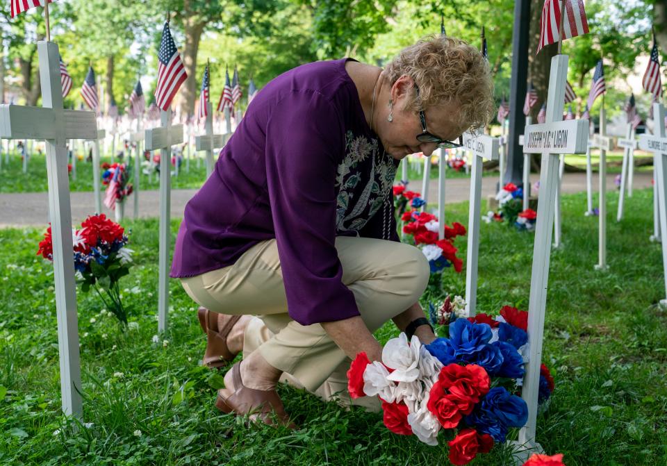 Pat Liegon places flowers for family members recognized for their service in the 6,160 crosses on display for Memorial Day in Henderson's Central Park Thursday, May 16, 2024.