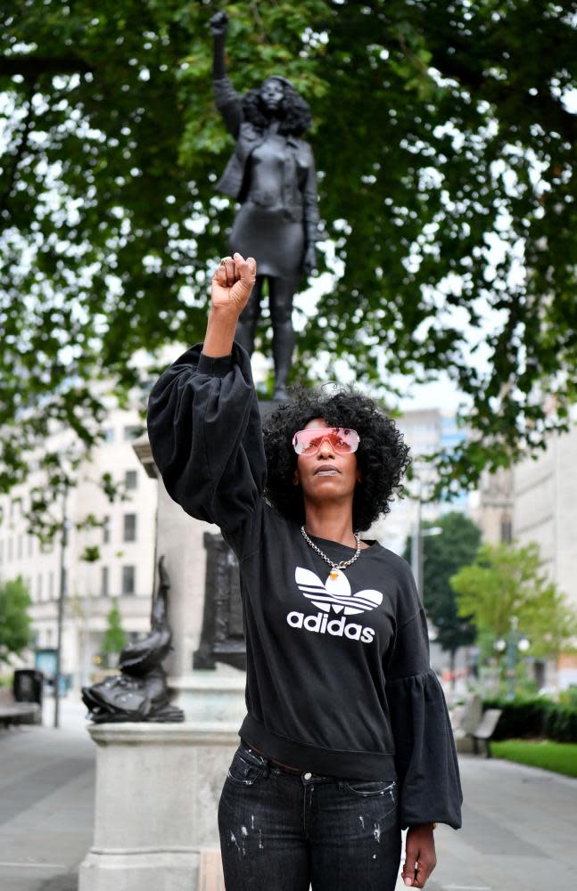 Jen Reid poses for a photograph in front of the sculpture of herself