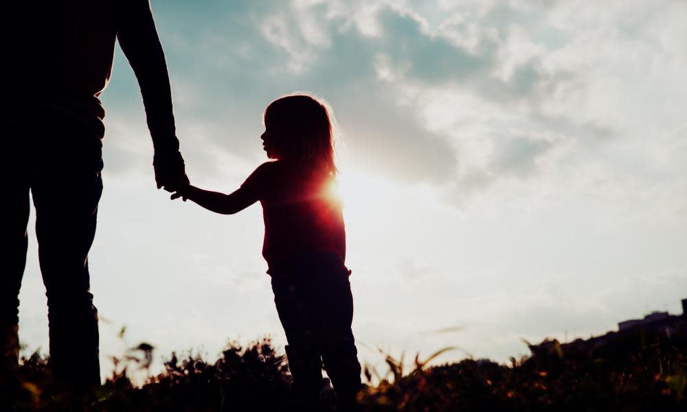 Silhouette of girl holding a parent's hand.