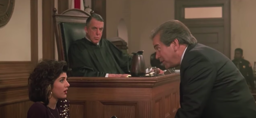 A woman sits on trial being questioned by a lawyer