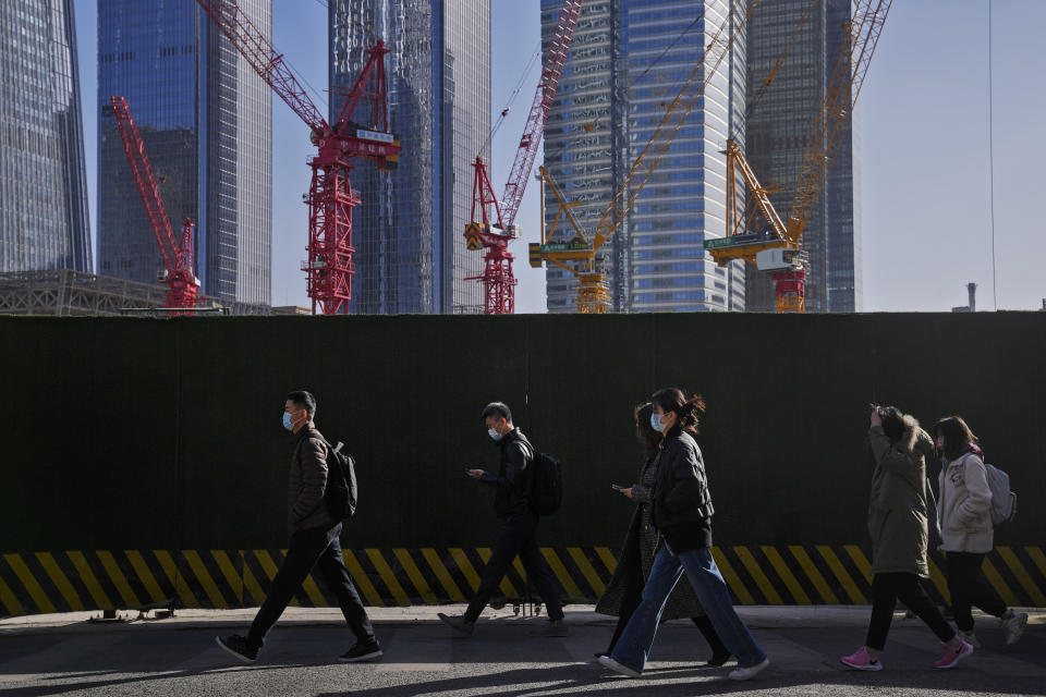 FILE - People wearing face masks walk by construction cranes near office buildings at the central business district in Beijing on March 15, 2023. China’s recovery from the pandemic and strong demand in India will drive strong growth in Asia this year, the Asian Development Bank said in a report issued Tuesday, April 4. (AP Photo/Andy Wong, File)