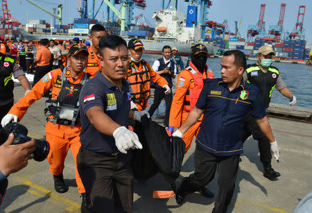 Rescue team members carry a body bag with the remains of a passenger of Lion Air, flight JT610, that crashed into the sea, at the Tanjung Priok port in Jakarta, Indonesia. REUTERS/Stringer