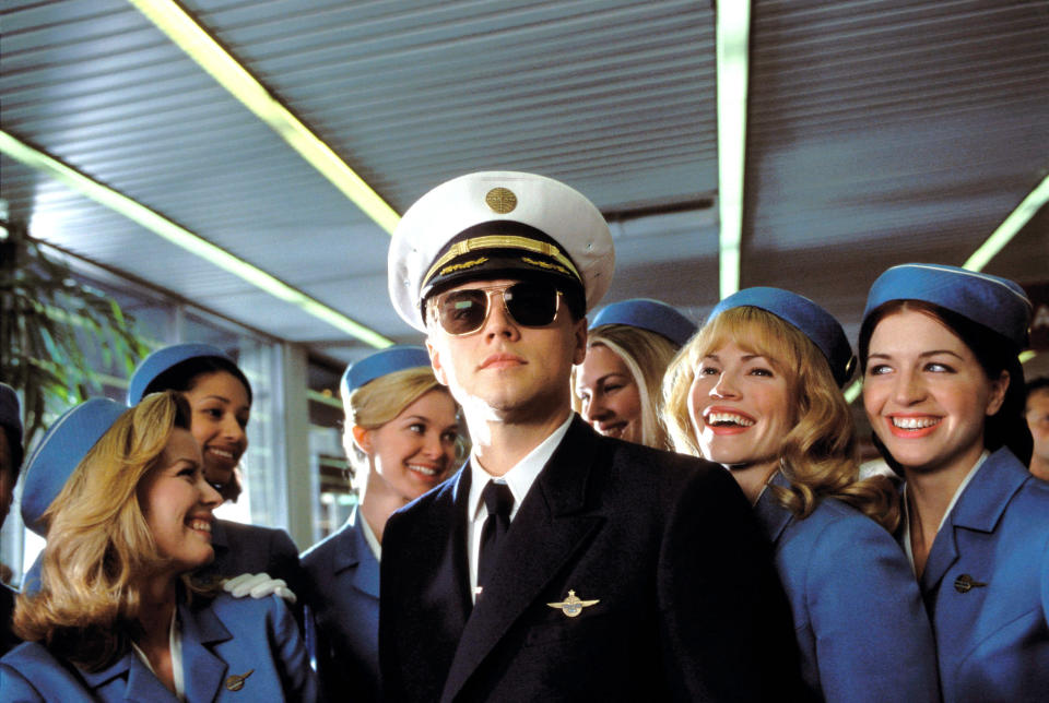 Leonardo DiCaprio dressed as a pilot surrounded by flight attendants