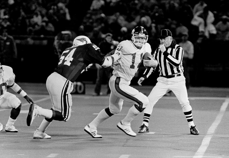 St. Louis Cardinals E.J. Junior (54) attempts to take down New York Giants quarterback Phil Simms (11) during a 1985 game in St. Louis.