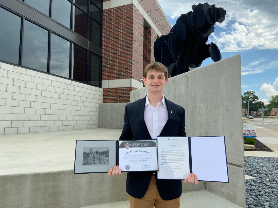 Luke Monk stands in front of the Northside High School bear mascot with his associates degree from UAFS and acceptance letter from Westpoint U.S. Military Academy.