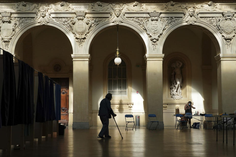 A voter exits a voting booth as they vote for the regional elections in Lyon, central France, Sunday, June 20, 2021. The elections for leadership councils of France's 13 regions, from Brittany to Burgundy to the French Riviera, are primarily about local issues like transportation, schools and infrastructure. But leading politicians are using them as a platform to test ideas and win followers ahead of the April presidential election. (AP Photo/Laurent Cipriani)