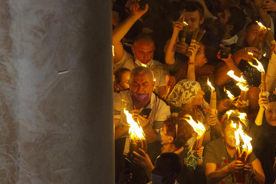 Christian pilgrims hold candles as they gather during the ceremony of the Holy Fire at Church of the Holy Sepulchre, where many Christians believe Jesus was crucified, buried and rose from the dead, in the Old City of Jerusalem, Saturday, May 1, 2021. Hundreds of Christian worshippers took use of Israel's easing of coronavirus restrictions Saturday and packed a Jerusalem church revered as the site of Jesus' crucifixion and resurrection for an ancient fire ceremony ahead of Orthodox Easter. (AP Photo/Ariel Schalit)