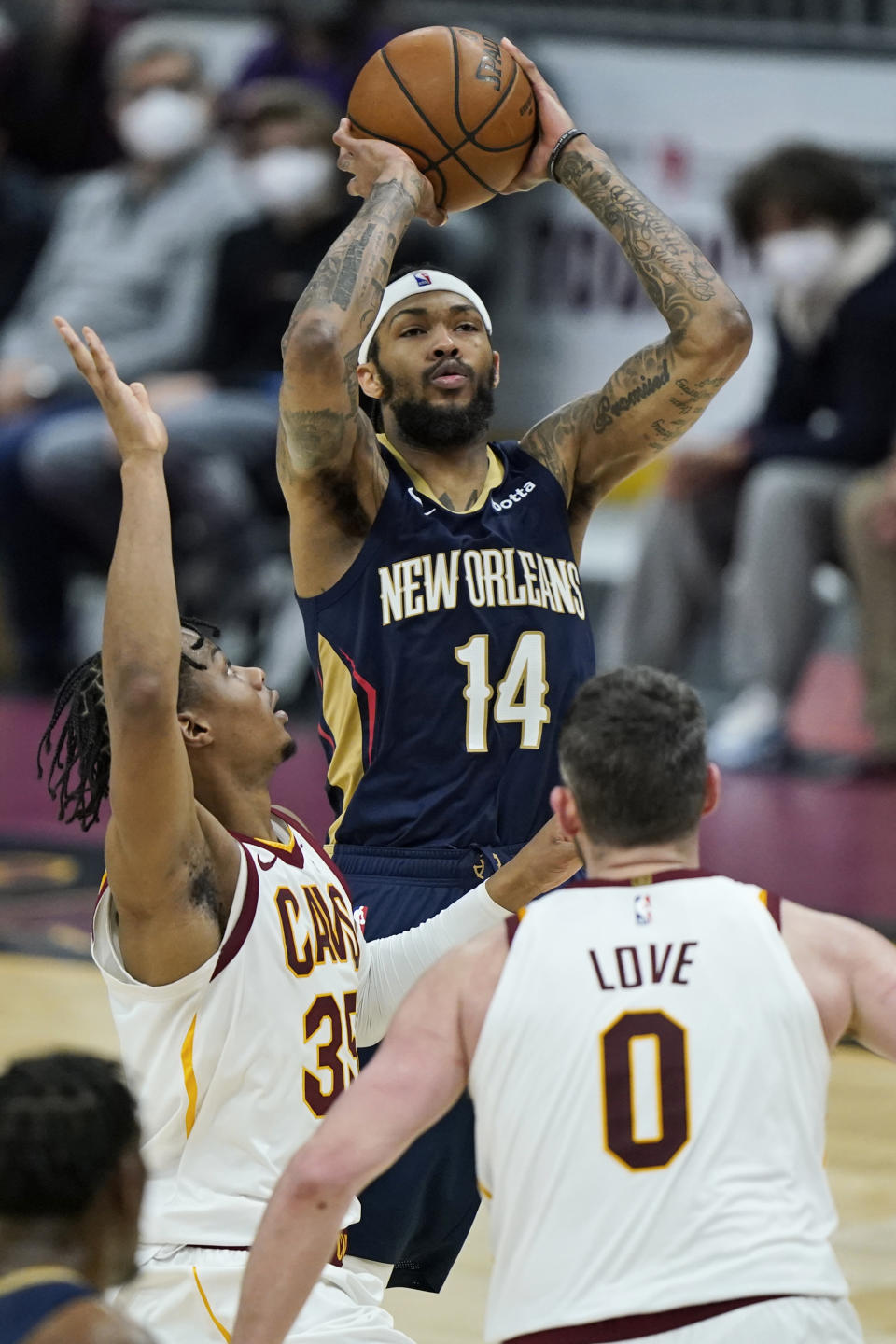 New Orleans Pelicans' Brandon Ingram, center, shoots over Cleveland Cavaliers' Isaac Okoro, left, and Kevin Love, right, in the second half of an NBA basketball game, Sunday, April 11, 2021, in Cleveland. (AP Photo/Tony Dejak)