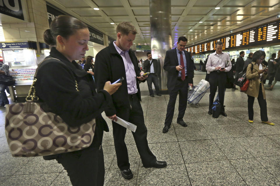 This Thursday, May 9, 2013 photo shows evening rush hour commuters looking at their smart phones while waiting for trains at the Long Island Railroad area inside Penn Station in New York. The busiest passenger train station in the United States, gateway to the biggest city in the nation, is a 1960s-era, utilitarian labyrinth built in what is essentially the basement of Madison Square Garden. Two decades after ambitious plans were unveiled to improve Penn Station while expanding it into the massive Beaux Arts post office building across the street, there are few visible signs of change. (AP Photo/Mary Altaffer)