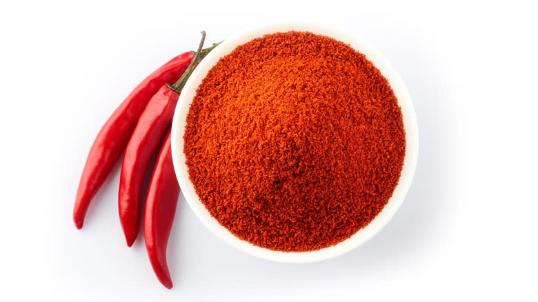 bowl of chili powder with three chilis on the side
