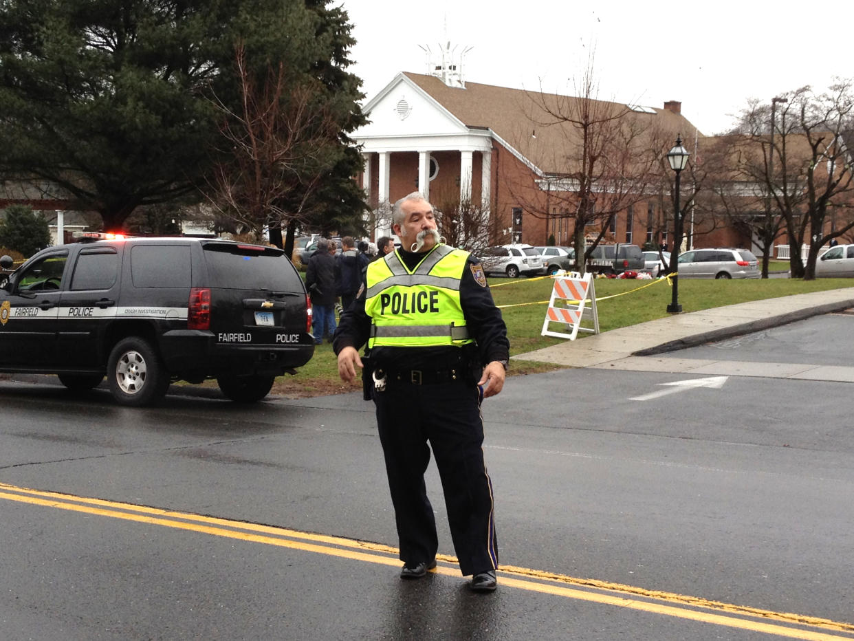 A police officer standing in the street directs traffic outside a funeral for Sandy Hook shooting victims.