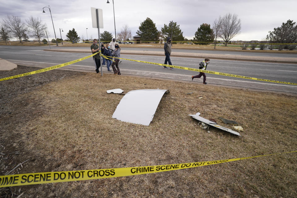 People look over debris that fell off a plane that shed parts over a neighborhood in Broomfield, Colo., Saturday, Feb. 20, 2021. The plane was making an emergency landing at nearby Denver International Airport. (AP Photo/David Zalubowski)