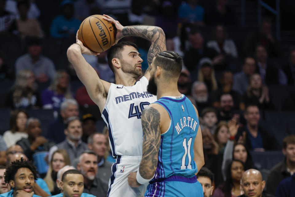 Memphis Grizzlies guard John Konchar, left, looks to pass against Charlotte Hornets forward Cody Martin during the first half of an NBA basketball game in Charlotte, N.C., Saturday, Feb. 10, 2024. (AP Photo/Nell Redmond)