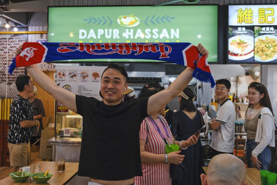 A chinese soccer fan takes a photograph in front of Singaporean goalkeeper Hassan Sunny's food stall in Singapore, Friday, June 14, 2024. Chinese soccer fans have poured their love into Hassan's food stall after his performance in a game this week indirectly helped China advance to the third qualifying round for the World Cup in 2026. (AP Photo/Tim Chong)