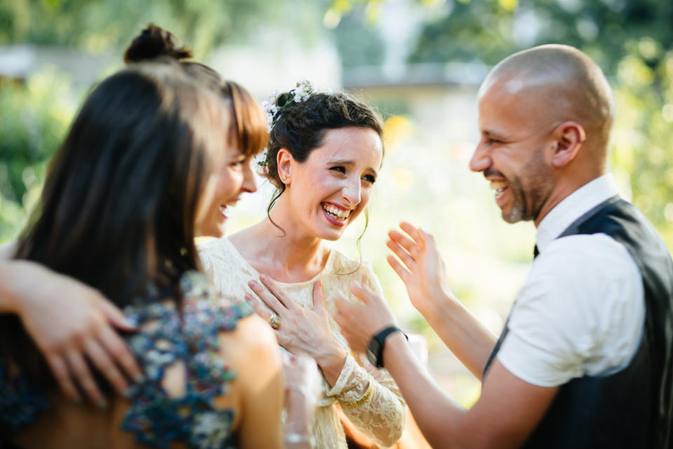 Two brides laugh with friends at their wedding