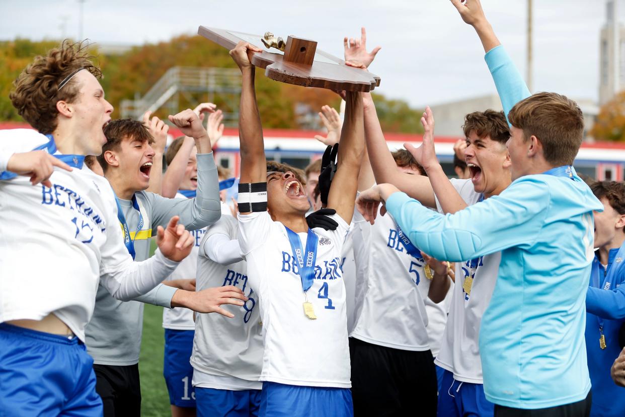 Bethany Christian senior Shemaya Magatti (4) raises the Class 1A boys soccer state championship trophy after the Bruins beat Forest Park 1-1 (3-1 penalty kicks) in the title game on Saturday, October 28, 2023, at Carroll Stadium in Indianapolis.