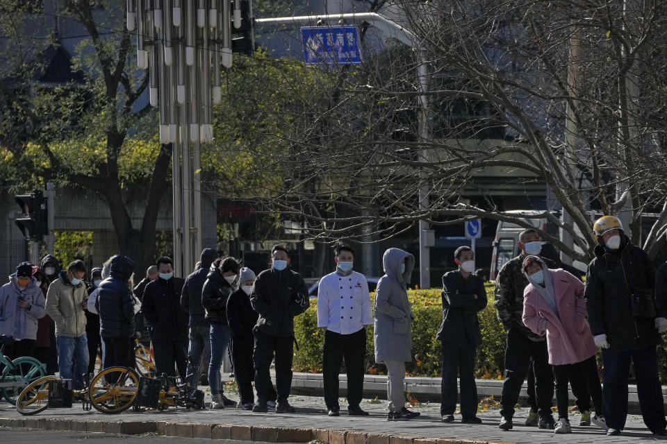 Residents stand in line for their routine COVID-19 tests in freezing cold temperatures near the site of last weekend's protest in Beijing, Wednesday, Nov. 30, 2022. China's ruling Communist Party has vowed to "resolutely crack down on infiltration and sabotage activities by hostile forces," following the largest street demonstrations in decades staged by citizens fed up with strict anti-virus restrictions. (AP Photo/Andy Wong)