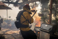 A firefighter gets caught off-guard by a flare up of the Palisades Fire in the Highlands neighborhood in the Pacific Palisades area of Los Angeles, Monday, Oct. 21, 2019. (AP Photo/Christian Monterrosa)
