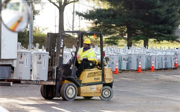 In this Thursday, Nov. 1, 2012, file photograph, PSE&amp;G employee Percy Thompson III unloads new electrical transformers as New Jersey's biggest utility rebuilds its grid after Superstorm Sandy.