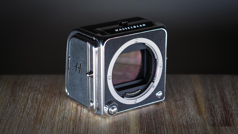 The Hasselblad 907X & CFV 100C medium format camera with digital back, on a wooden table with artistic lighting