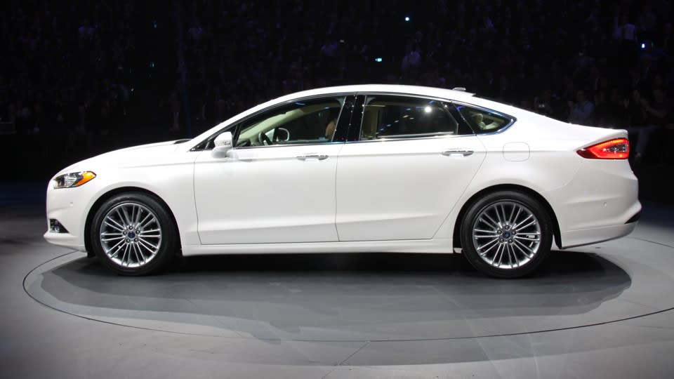 Later this year, Ford Motor Co. will launch this: the 2013 Ford Fusion midsize sedan in three variations — including a plug-in hybrid that gets 100 mpg, besting every other liquid-powered vehicle for sale to the American public. It could be a winning equation, but there's a few key variables Ford hasn't revealed. The current Fusion has turned into a mainstay of Ford's lineup, and the most popular car built by an American automaker, with sales hitting 248,067 in 2011. For its redesign, Ford will run the same play it's called on with the smaller Fiesta and Focus −- build one version of the Fusion for sale worldwide, using the Mondeo name in Europe and elsewhere, to lower costs while raising quality. Assembled in Mexico and Michigan, styled in Europe to follow the new Ford global look, two of its three engines will be built in Spain and England.