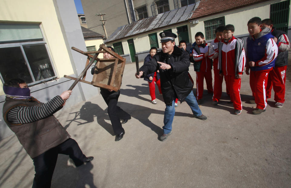 Students stand as policeman and teacher try to defend them against intruder during anti-violence exercise at school in Jinan