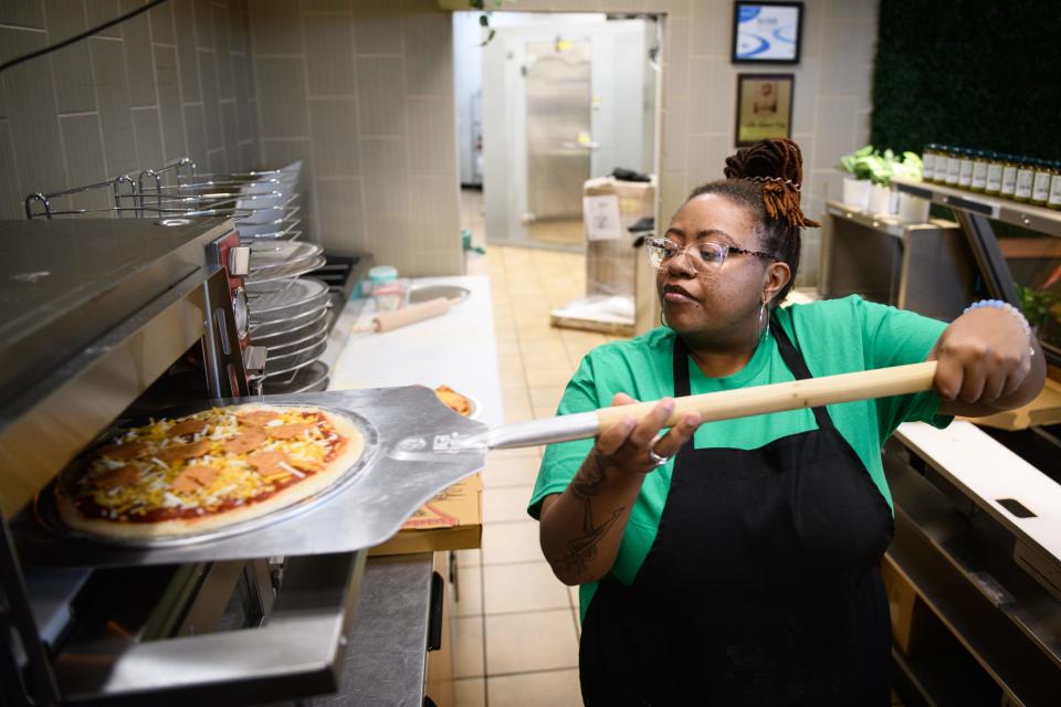 Ashley Sutton tosses a pizza in the oven at The Vegan Spot at 3421 Murchison Road.