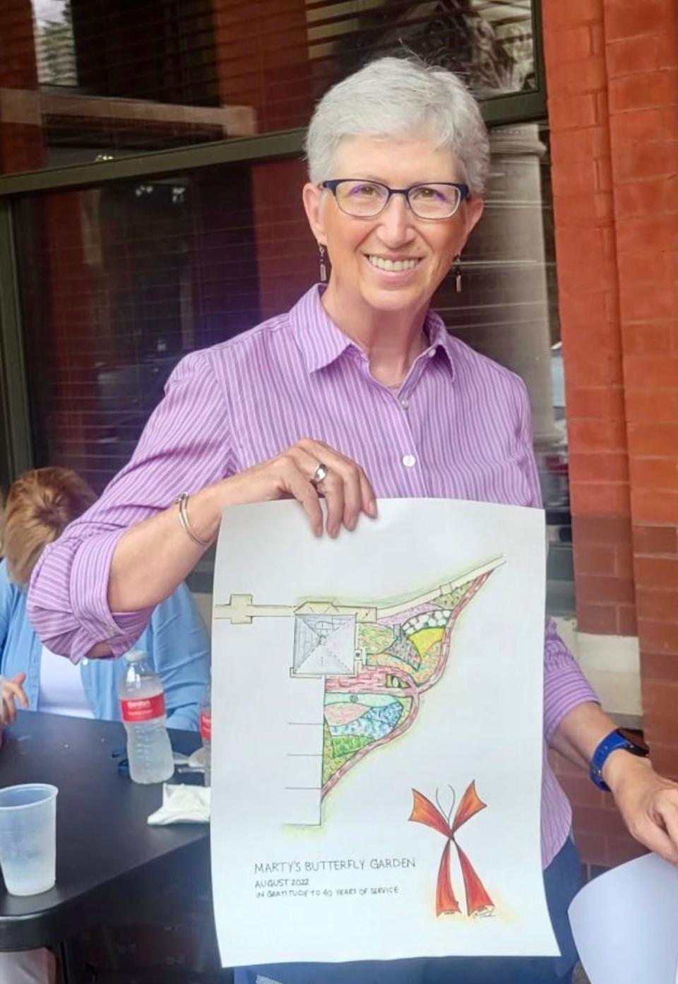 Marty Davis, who recently retired from Crown Hill Funeral Home and Cemetery after 40 years, holds a sketch of her retirement gift, a butterfly garden which will be installed near the entrance to Crown Hill in Indianapolis.