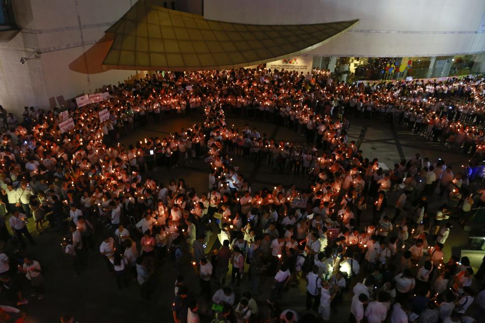 People hold candles as they form a peace sign during an anti-violence campaign in central Bangkok