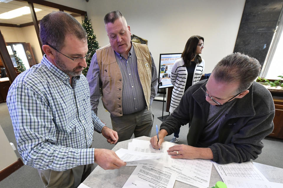 Andrson County Kentucky Board of Elections member Steve Ashburn, right, signs off on the results of the remcanvass of the votes of the election for Kentucky Governor in Lawrenceburg, Ky., Thursday, Nov. 14, 2019. Right is Anderson Co. Clerk Jason Denny, and center is Anderson Co. Sheriff Joe Milam. Election officials across Kentucky have started double-checking vote totals that show Republican Gov. Matt Bevin trailing Democrat Andy Beshear by more than 5,000 votes. (AP Photo/Timothy D. Easley)