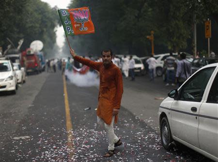 A supporter of India's main opposition Bharatiya Janata Party (BJP) waves the party's flag during celebrations before India's Hindu nationalist Narendra Modi was crowned as the prime ministerial candidate for the BJP outside the party headquarters in New Delhi September 13, 2013. REUTERS/Ahmad Masood