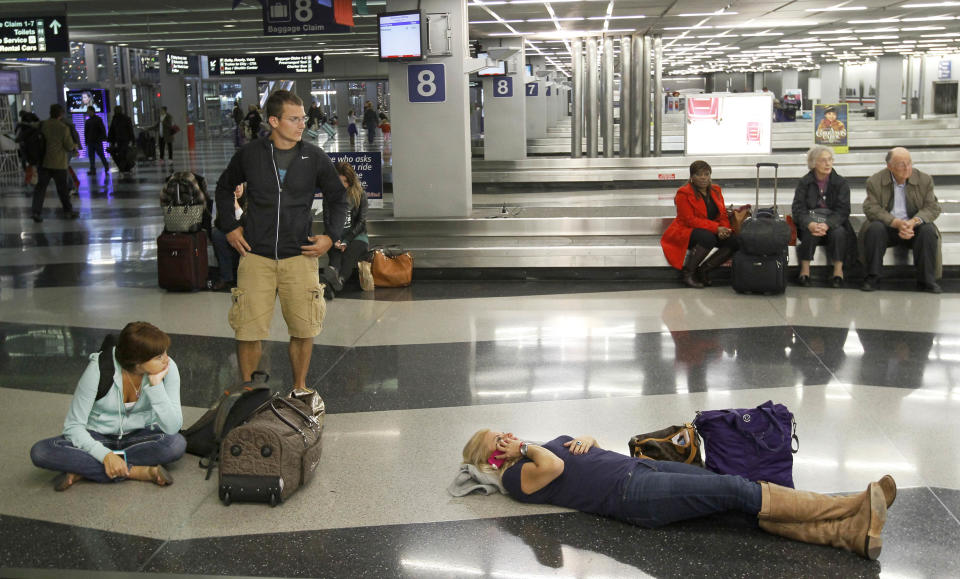 FILE - In this Wednesday, Nov. 21, 2012, file photo, travelers wait for their baggage at an American Airlines baggage claim at Chicago's O'Hare International Airport. A massive winter storm is disrupting travel plans for tens of thousands of fliers trying to get home after Christmas on Wednesday, Dec. 26, 2012. Snow, thunderstorms, sleet, tornados and high winds have grounded planes in the nation's midsection and are expected to slow operations on the East Coast. (AP Photo/Charles Rex Arbogast)