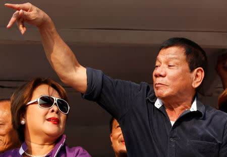 Presidential candidate Rodrigo "Digong" Duterte throws election souvenirs to supporters next to Senatorial candidate Sandra Cam during election campaigning in Malabon, Metro Manila in the Philippines April 27, 2016. REUTERS/Erik De Castro