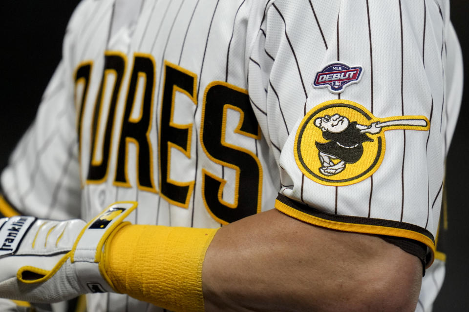 San Diego Padres' Brett Sullivan wears a patch to commemorate his major league debut as he walks back to the dugout after lining out during the third inning of a baseball game against the Atlanta Braves, Tuesday, April 18, 2023, in San Diego. (AP Photo/Gregory Bull)