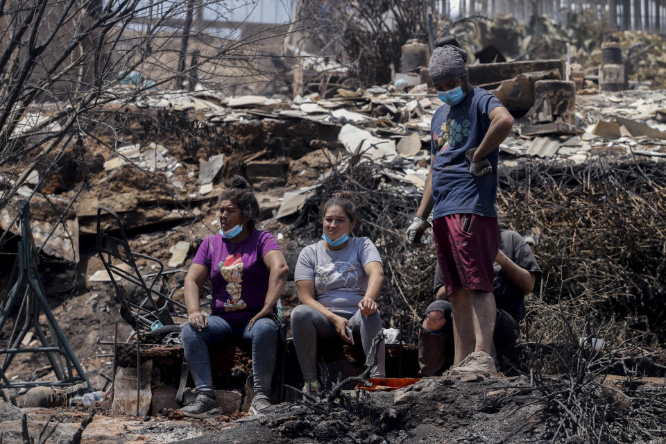 Locals take a break as they clean the rubble of burnt-out houses after forest fires reached their neighborhood in Vina del Mar, Chile, Sunday, Feb. 4, 2024. (AP Photo/Cristobal Basaure)