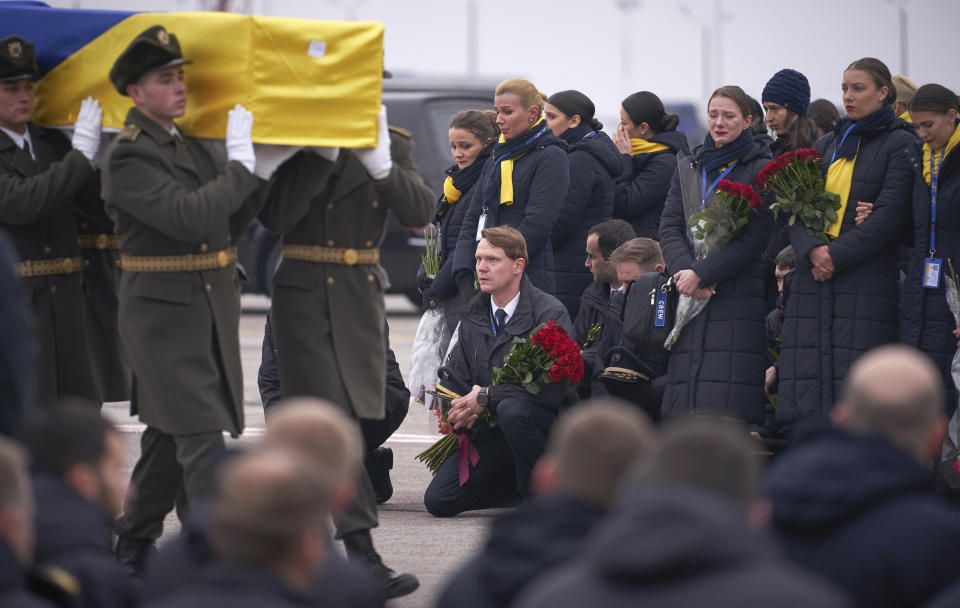 In this photo provided by the Ukrainian Presidential Press Office, colleagues of the flight crew members of the Ukrainian 737-800 plane that crashed on the outskirts of Tehran react as honor guard carry a coffin of the one of the eleven victims, at Borispil international airport outside Kyiv, Ukraine, Sunday, Jan. 19, 2020. An Ukrainian passenger jet carrying 176 people has crashed just minutes after taking off from the Iranian capital's main airport on Jan. 8, 2020. (Ukrainian Presidential Press Office via AP)