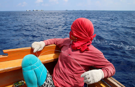 A hooded Philippine fisherman fishes at the disputed Scarborough Shoal April 6, 2017. Picture taken April 6, 2017. REUTERS/Erik De Castro