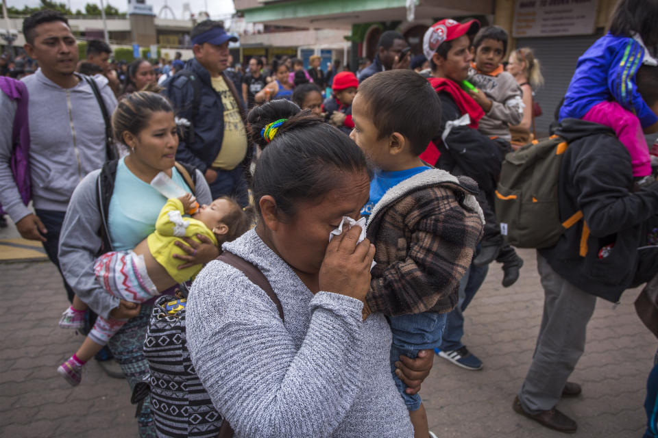 Adults in the migrant caravan carry small children.