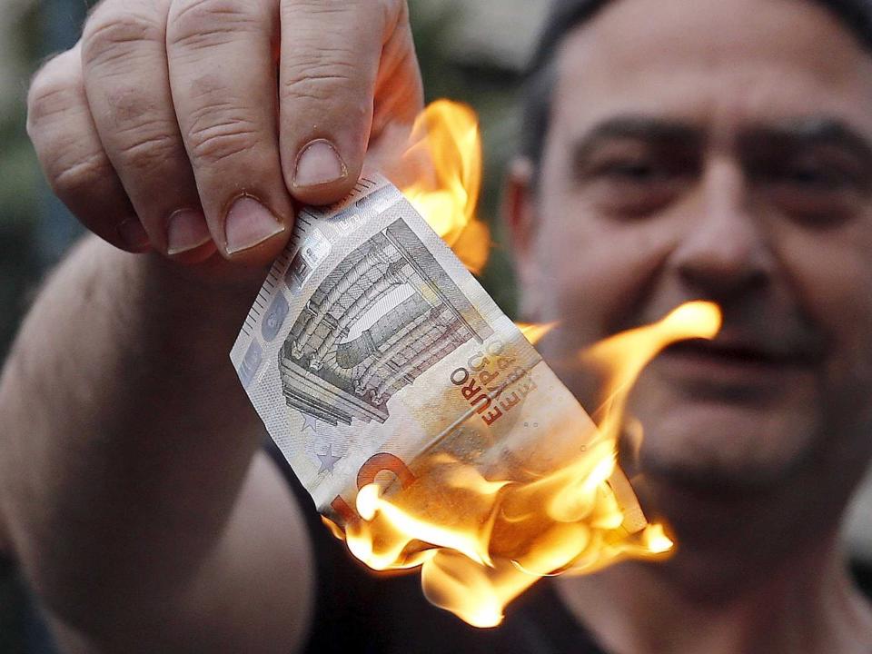 An anti-austerity protester burns a euro note during a demonstration outside the European Union (EU) offices in Athens, Greece June 28, 2015. Greece said it may impose capital controls and keep its banks shut on Monday after creditors refused to extend the country's bailout and savers queued to withdraw cash, taking Athens' standoff with the European Union and the International Monetary Fund to a dangerous new level.