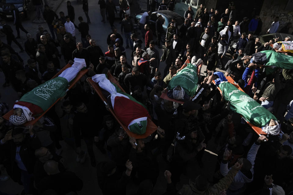 Mourners carry the bodies of six Palestinians draped in the Hamas flags during their funeral in the West Bank city of Jenin on Sunday, Jan. 7, 2024. Six Palestinians and a member of Israel's paramilitary border police were killed in confrontations in a hot spot of violence in the Israeli-occupied West Bank, the Palestinian Health Ministry and the Israeli military said Sunday. (AP Photo/Majdi Mohammed)