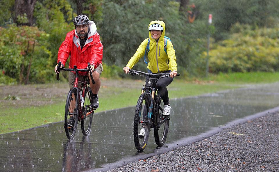 Joel Barrera, of Natick, Cochituate Rail Trail Advisory Committee, and Alexi Conine, of Boston, arrive in the rain for the official Mass. DOT ribbon cutting ceremony of the Framingham-Natick Rail Trail, September 28, 2021. 