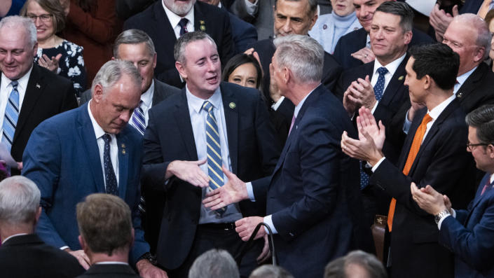 Kevin McCarthy surrounded by Republican lawmakers applauding, as he stretches out his hand to shake Rep. Brian Fitzpatrick&#39;s.