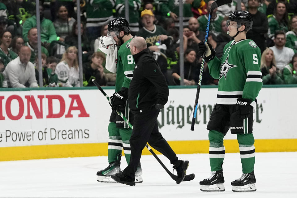 Dallas Stars' Tyler Seguin, left, is escorted off the ice by a staff member and Nils Lundkvist, after taking a hit to the face by Vegas Golden Knights' Alex Pietrangelo in the second period in Game 5 of an NHL hockey Stanley Cup first-round playoff series in Dallas, Wednesday, May 1, 2024. Pietrangelo recieved a penalty on the play. (AP Photo/Tony Gutierrez)