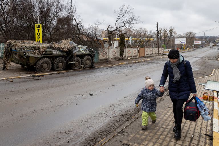 IRPIN, UKRAINE - MARCH 04: Civilians carry their belongings as the evacuate to safety across a contested bridge at the frontline between Bucha and Irpin City on March 04, 2022 in Irpin, Ukraine. Russia continues assault on Ukraine's major cities, including the capital Kyiv, a week after launching a large-scale invasion of the country. (Photo by Chris McGrath/Getty Images)