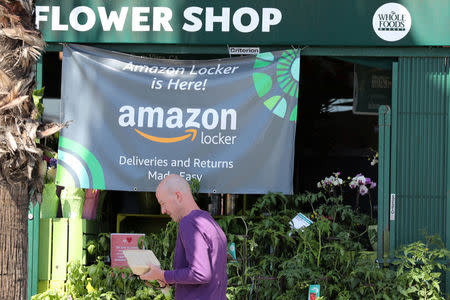 A man walks past an advert for Amazon Locker outside a Whole Foods Market store in Santa Monica, California, U.S. March 19, 2018. REUTERS/Lucy Nicholson